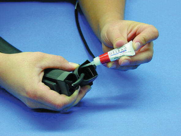 11. Remove the gable plug on the strap but keep the connection cable on. Apply glue along the whole edge inside the gable plug.